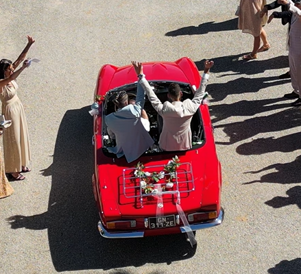 Photo des mariés sur une voiture rouge